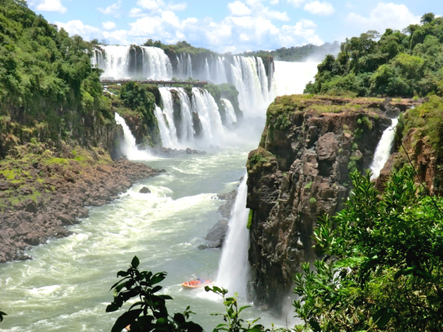 Панорама водопадов Игуасу с аргентинской стороны и лодка для водного шоу под водпадами внизу Панорама водопадов Игуасу с аргентинской стороны и лодка для водного шоу под водпадами внизу